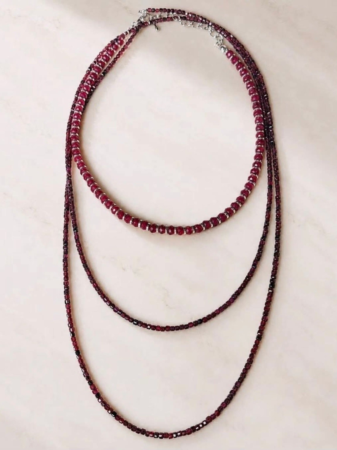 Layered garnet-toned beaded necklace with three graceful strands.