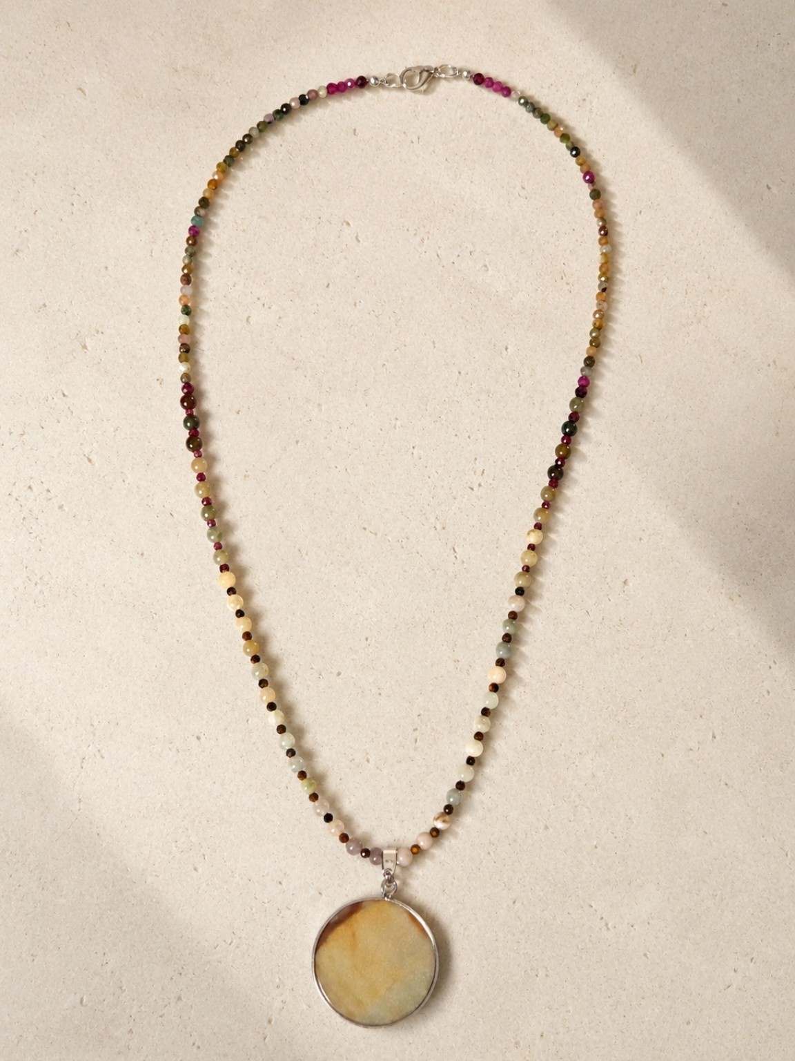 Delicate beaded necklace with a round pendant in warm golden tones.